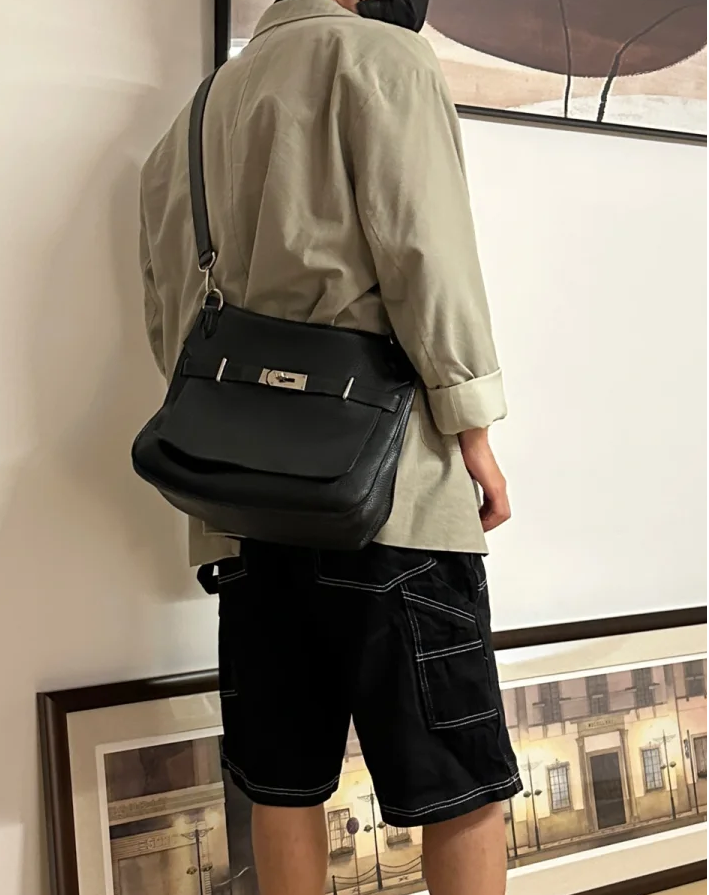 Man posing with mini jypsiere bag in black leather